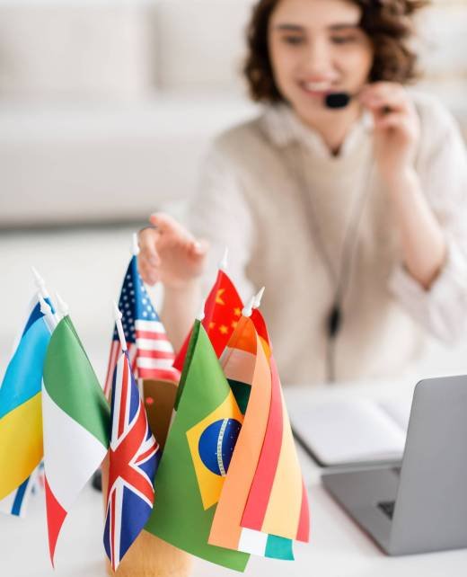 selective focus of various international flags near laptop and blurred language teacher working at home